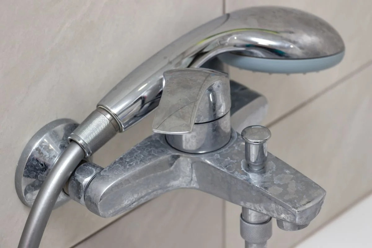 robinet et pommeau de douche avec des taches de calcaire dans une salle de bain