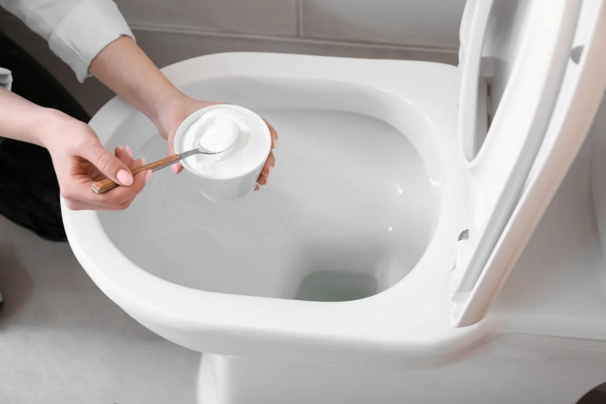 femme qui verse du bicarbonate dans les toilettes