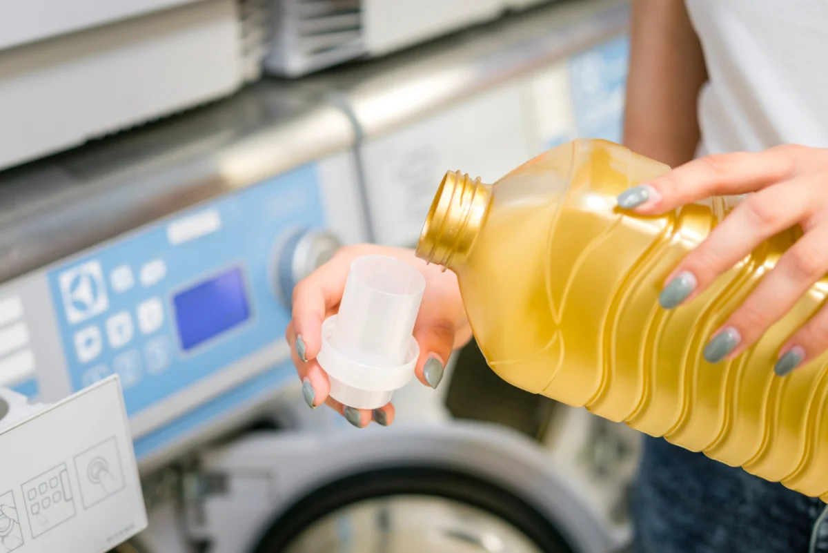 femme qui met du vinaigre blanc dans sa machine à laver