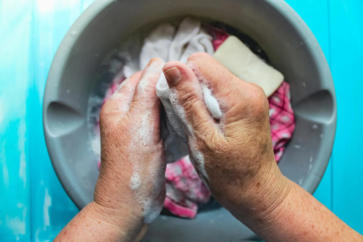 gros plan sur les mains d'une grand-mère qui nettoie une tache de graisse sur un vêtement