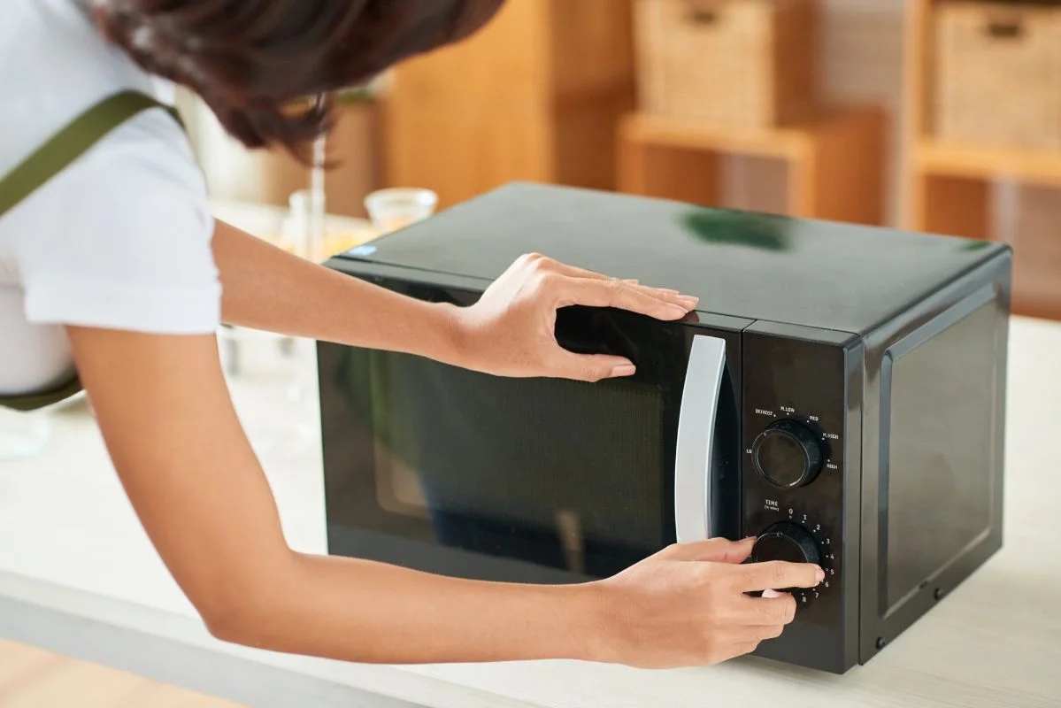 femme qui fait règle la durée sur son four micro-ondes