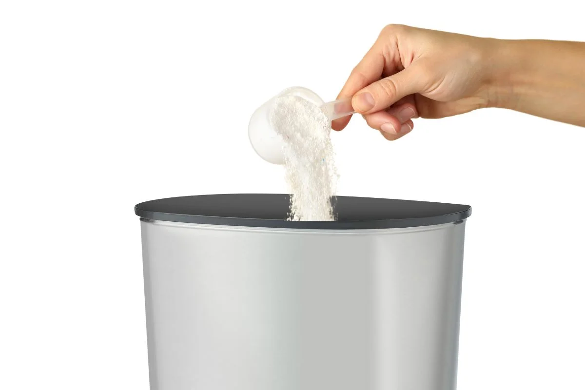 personne qui verse du bicarbonate de soude dans la poubelle