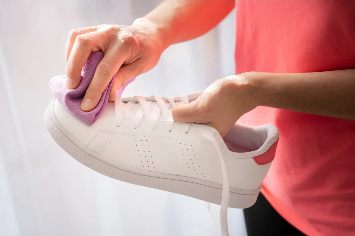 personne qui nettoie des baskets en cuir blanche