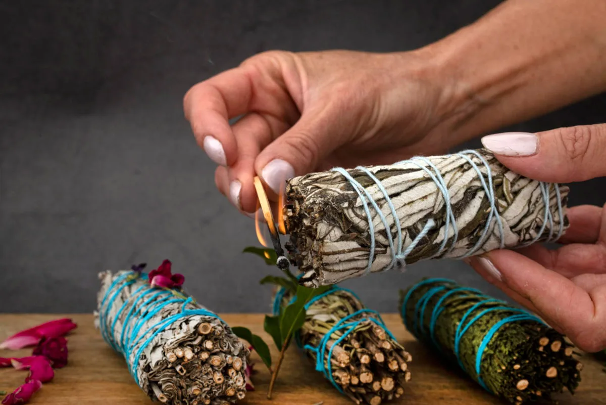 femme qui allume un bâton de fumigation avec une allumette