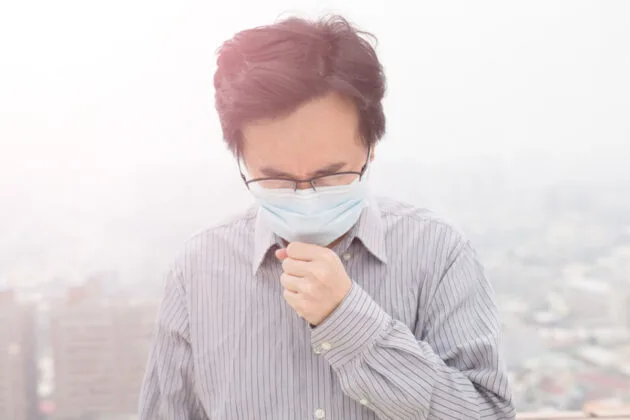 homme avec un masque sui souffre de la pollution de l'air