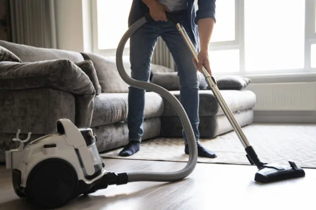 un homme qui passe l'aspirateur dans le salon